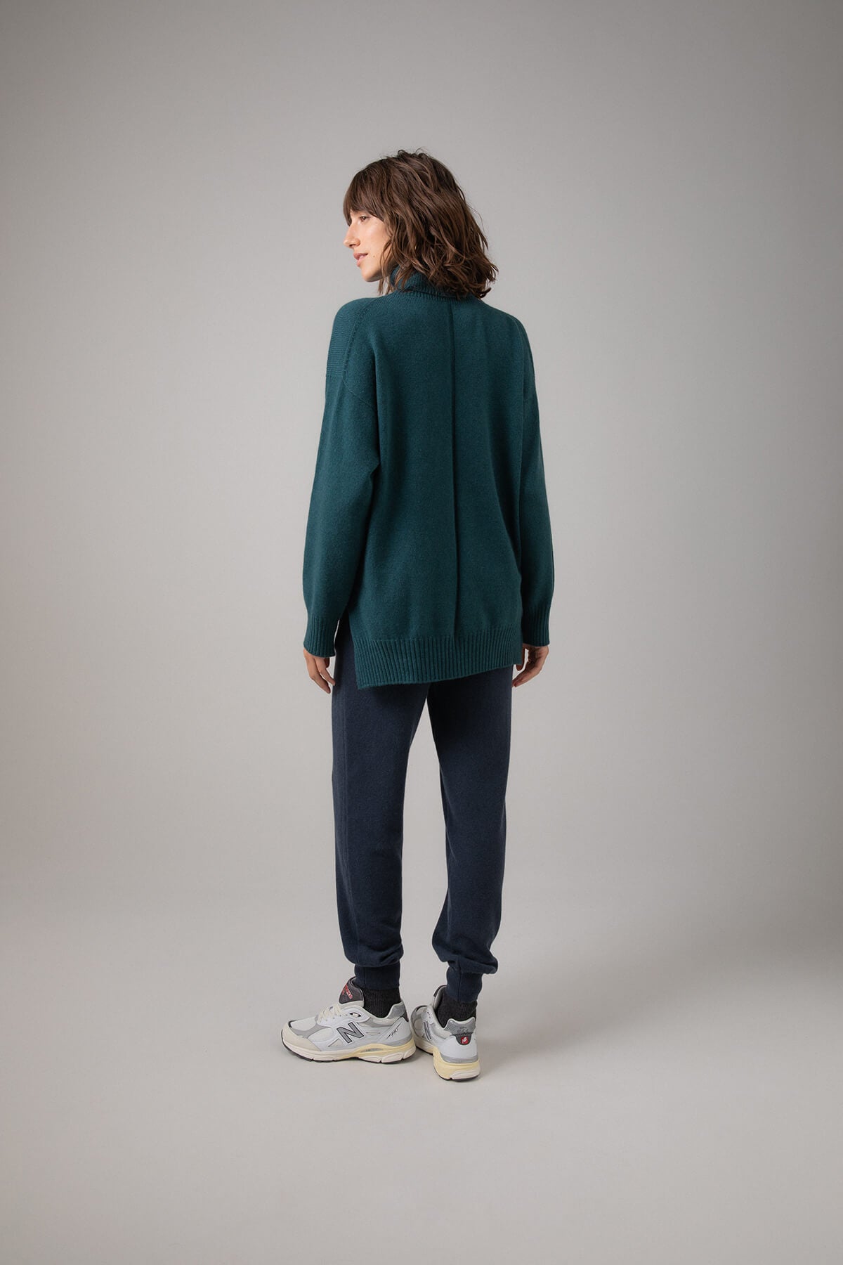 Back view of Johnstons of Elgin Women's Gauzy Cashmere Roll Neck with Stepped Hem in Mallard on a grey background KAI05100HC7126