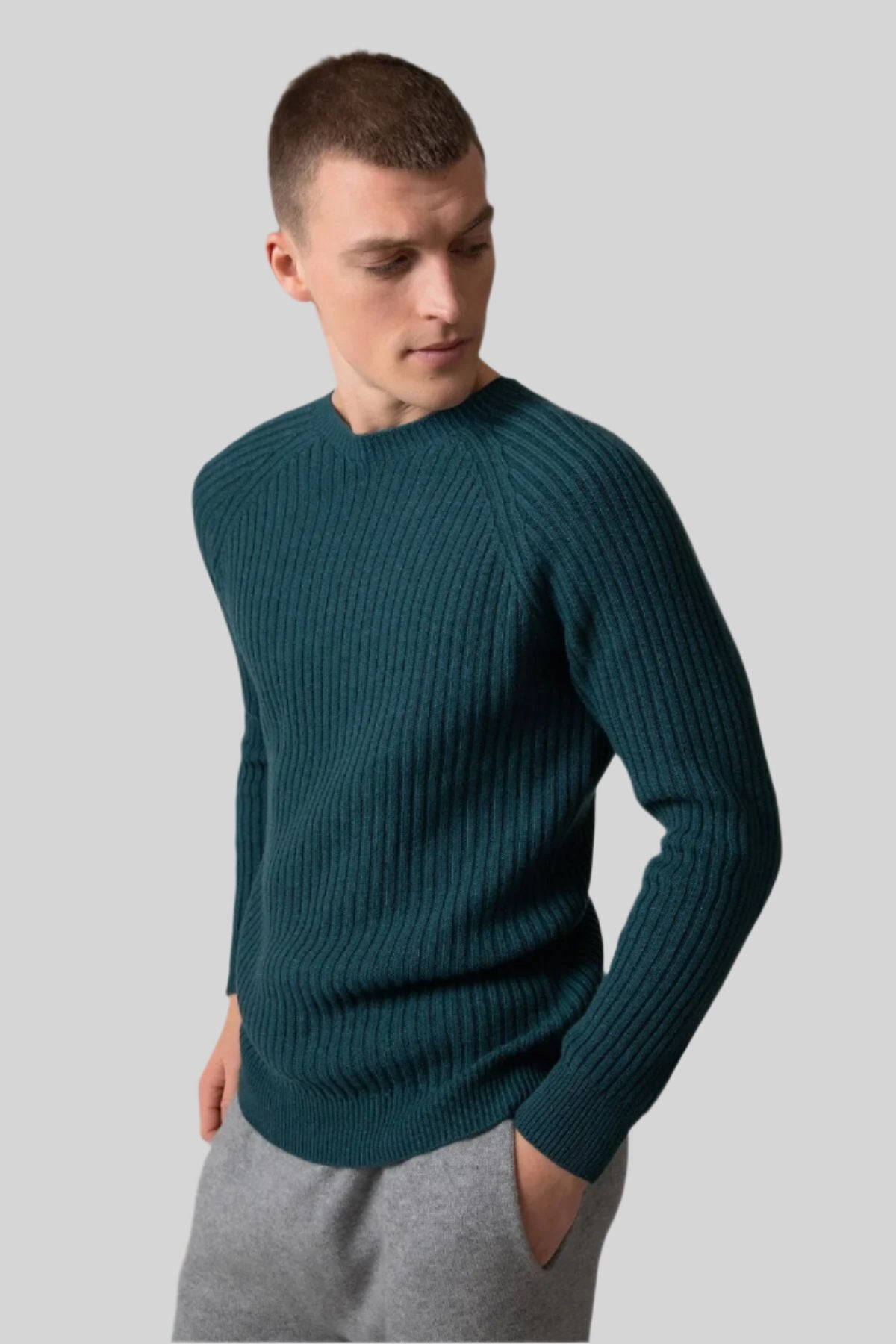 Johnstons of Elgin’s Men's Ribbed Cashmere Round Neck Jumper in mallard green on model wearing grey joggers on a grey background KAI05105HC7126