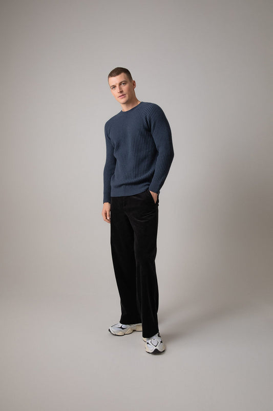 Johnstons of Elgin’s Men's Ribbed Cashmere Round Neck Jumper in Mazarine blue on model wearing black trousers on a grey background KAI05105SD7351