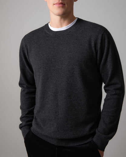 Johnstons of Elgin Men’s Cashmere Round Neck Jumper in Charcoal grey on model wearing black trousers on grey background KAI05117HA7165