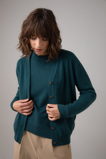 Johnstons of Elgin Women's Cashmere Boyfriend Cardigan in Mallard green worn with a matching Crew Neck on a grey background KAI05141HC7126
