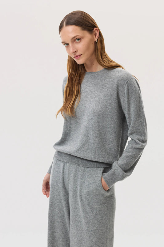 Model wears Johnstons of Elgin SS25 Women's Knitwear Light Grey Classic Cashmere Round Neck Sweater with matching cashmere culottes KAI05142HA0308