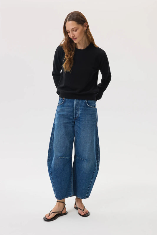 Model wearing Johnstons of Elgin SS25 Women's Knitwear Black Classic Cashmere Round Neck Sweater with blue barrel leg jeans and black sandals KAI05142SA0900
