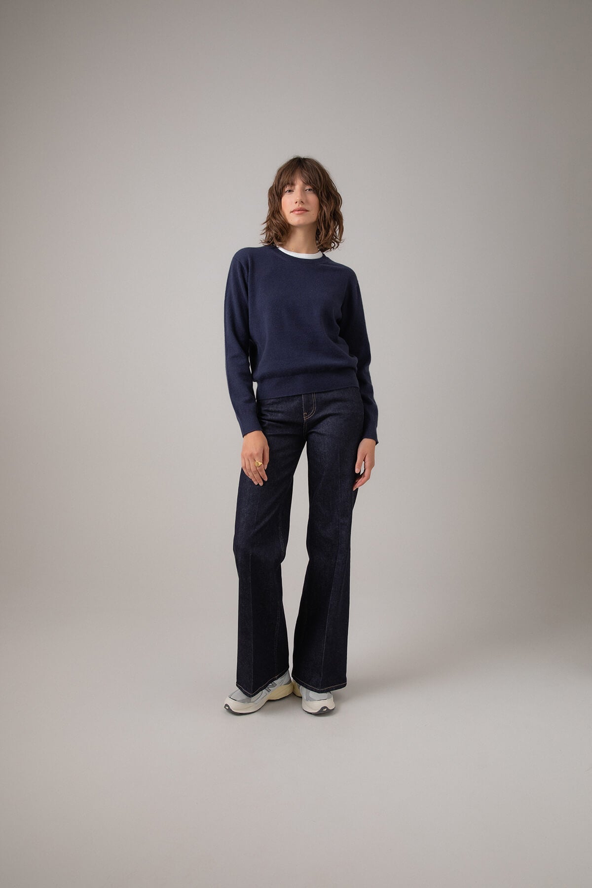  Johnstons of Elgin Classic Women's Cashmere Cropped Round Neck Jumper in Navy worn with Jeans on a grey background KAI05142SD0707