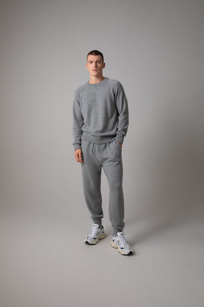 Johnstons of Elgin’s Men's Cashmere Donegal Joggers in Light grey on model wearing matching grey cashmere jumper on a grey background KAI05146004542