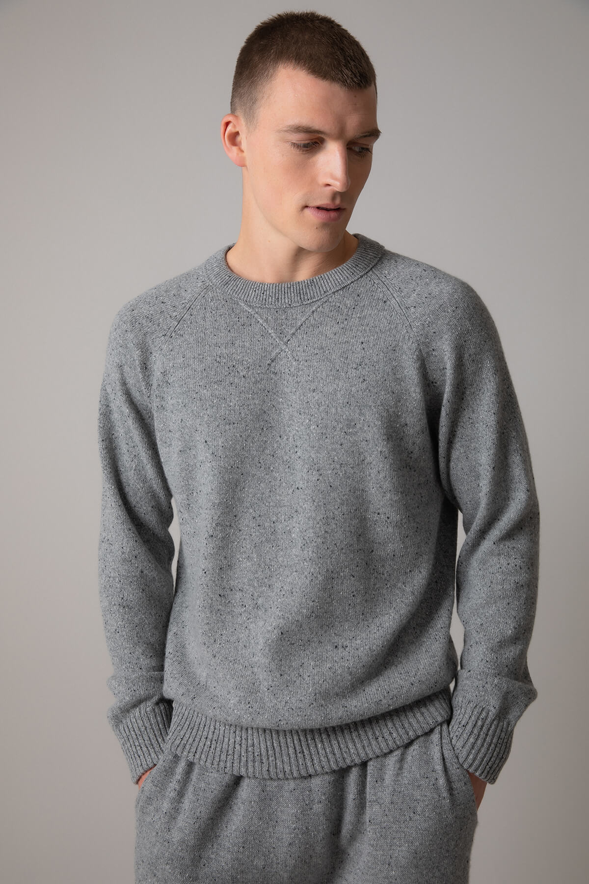 Johnstons of Elgin’s Men's Cashmere Donegal Sweatshirt in Light grey on model wearing matching grey joggers on a grey background KAA05147004542