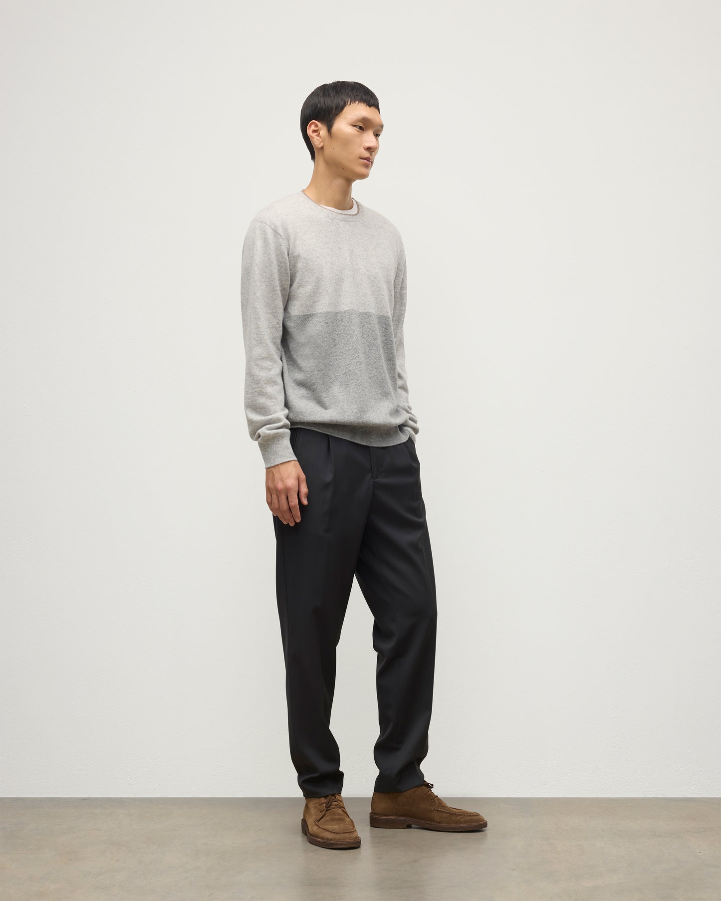 MODEL WEARING JOHNSTONS OF ELGIN MENS SHADED CREW SWEATER LIGHT GREY 100% CASHMERE OVER A WHITE T-SHIRT WITH GREY TROUSERS KAI05232Q25946