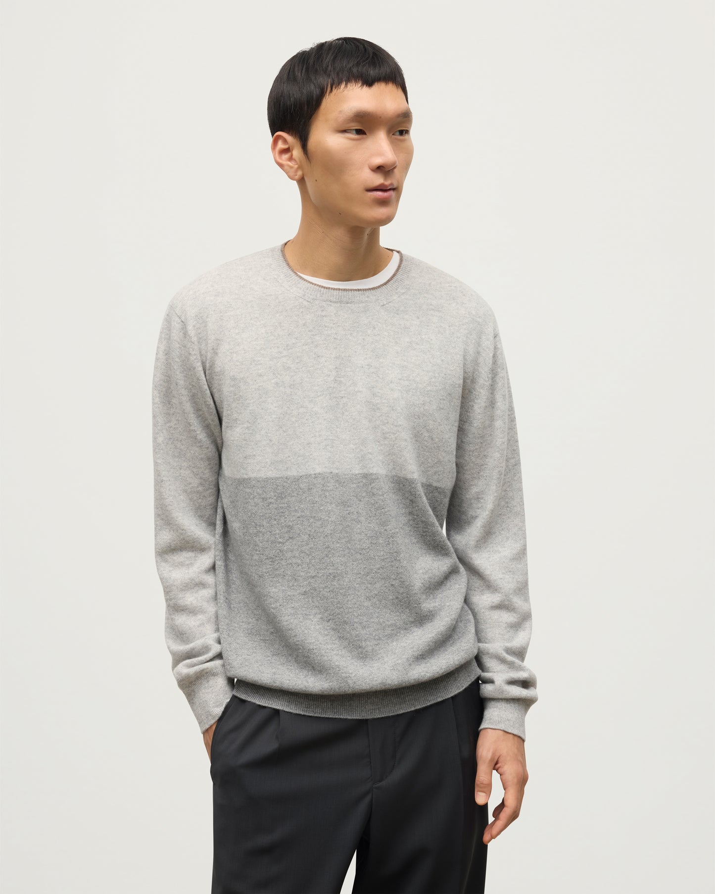 MODEL WEARING JOHNSTONS OF ELGIN MENS SHADED CREW SWEATER LIGHT GREY 100% CASHMERE OVER A WHITE T-SHIRT WITH GREY TROUSERS KAI05232Q25946