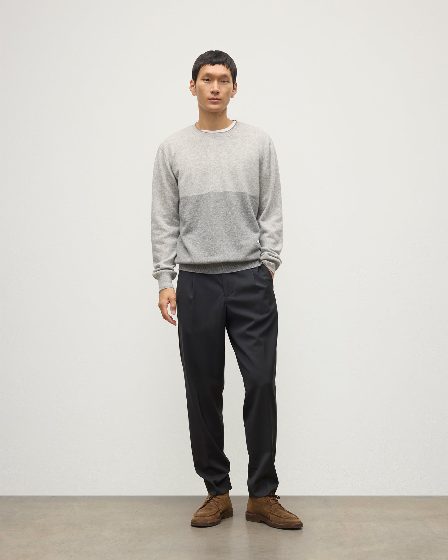 MODEL WEARING JOHNSTONS OF ELGIN MENS SHADED CREW SWEATER LIGHT GREY 100% CASHMERE OVER A WHITE T-SHIRT WITH GREY TROUSERS KAI05232Q25946