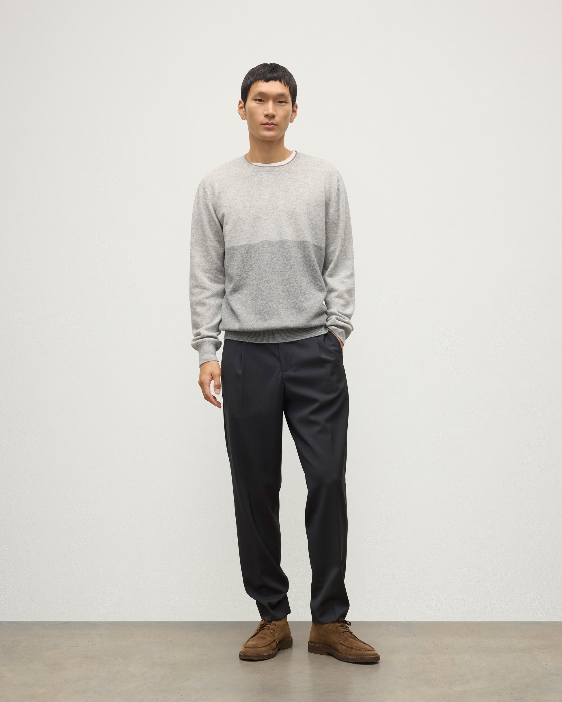 MODEL WEARING JOHNSTONS OF ELGIN MENS SHADED CREW SWEATER LIGHT GREY 100% CASHMERE OVER A WHITE T-SHIRT WITH GREY TROUSERS KAI05232Q25946