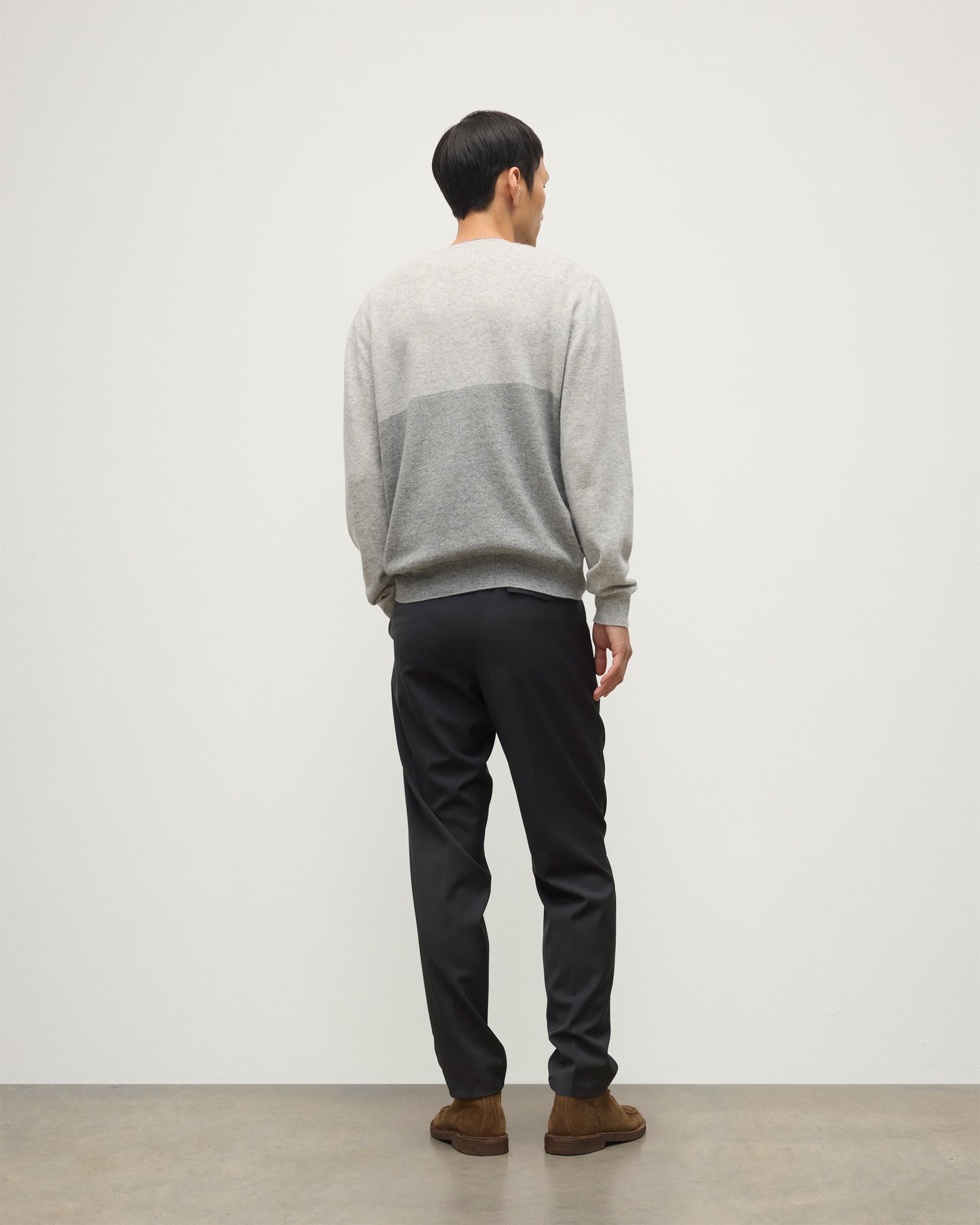 MODEL WEARING JOHNSTONS OF ELGIN MENS SHADED CREW SWEATER LIGHT GREY 100% CASHMERE OVER A WHITE T-SHIRT WITH GREY TROUSERS KAI05232Q25946