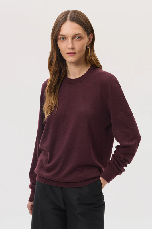 Female model wearing Johnstons of Elgin SS25 Unisex Knitwear Rosewood Superfine Cashmere V Neck Jumper against a white backdrop  KAI05242SB7255