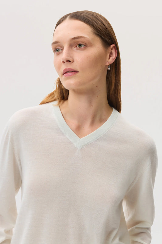 Female model wearing Johnstons of Elgin SS25 Unisex Knitwear White Superfine Cashmere V Neck Sweater on a white backdrop KAI05242HA0327