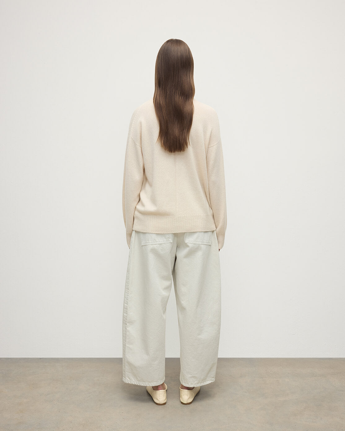 Model wears Johnstons of Elgin AW25 Women's Knitwear Champagne Gauzy Cashmere Cream Roll Neck Jumper Back View KAI05324SA0502