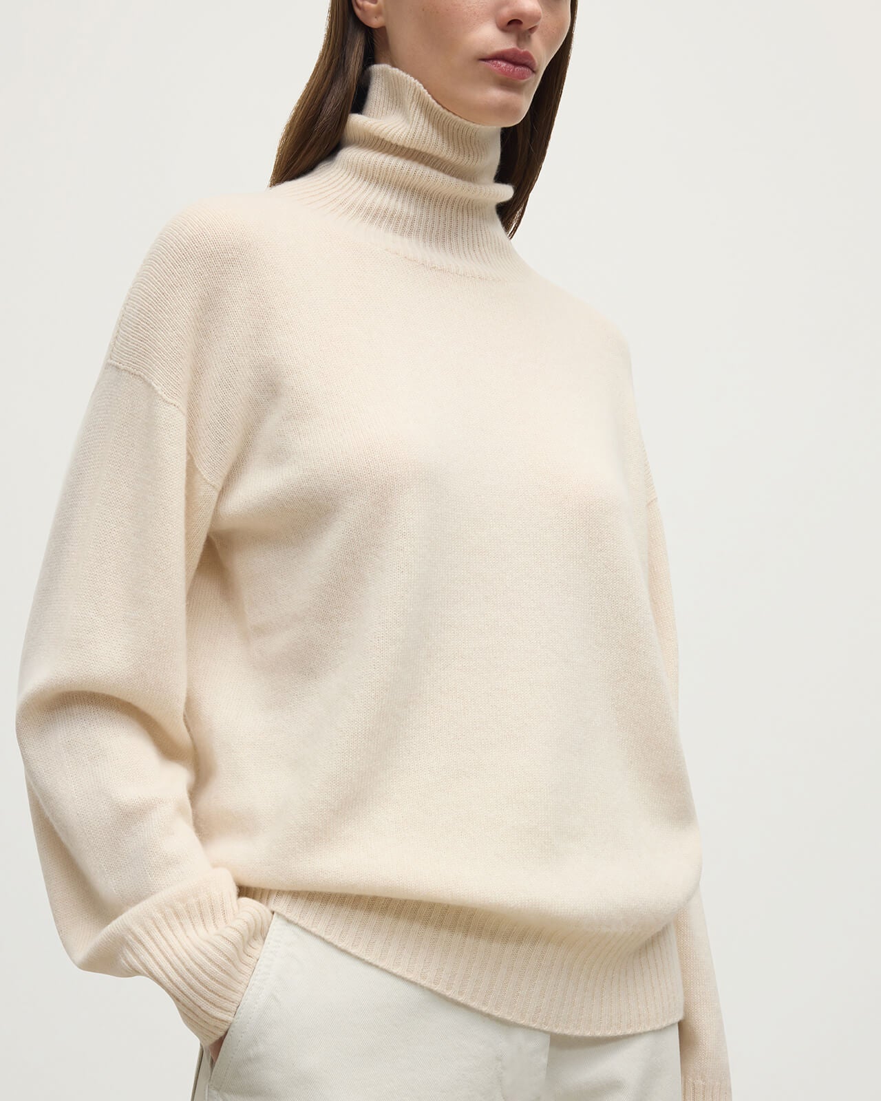 Model wears Johnstons of Elgin AW25 Women's Knitwear Champagne Gauzy Cashmere Cream Roll Neck Jumper Close Up  KAI05324SA0502