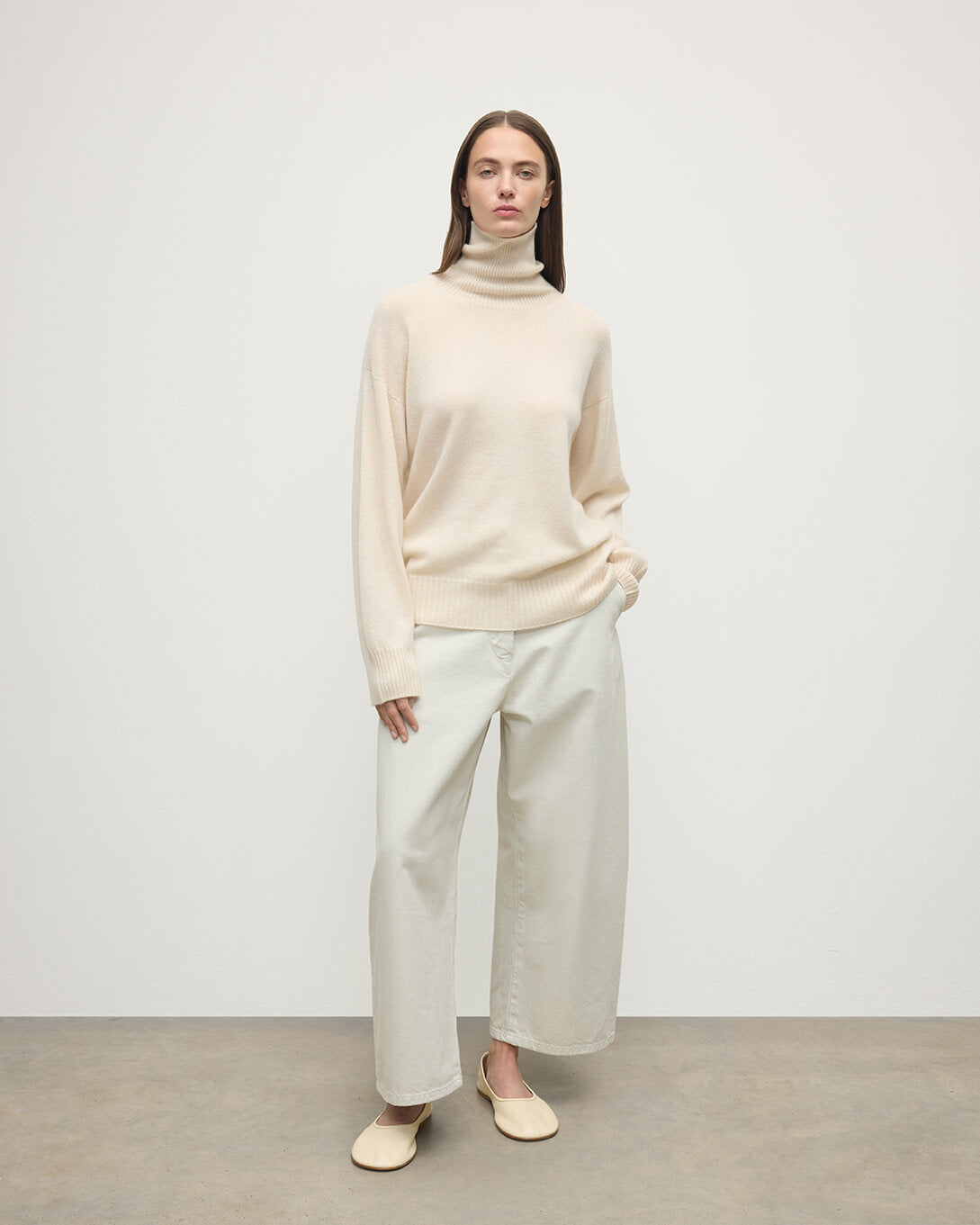 Model wears Johnstons of Elgin AW25 Women's Knitwear Champagne Gauzy Cashmere Cream Roll Neck Jumper Front View KAI05324SA0502