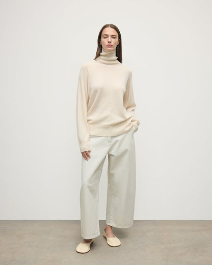 Model wears Johnstons of Elgin AW25 Women's Knitwear Champagne Gauzy Cashmere Cream Roll Neck Jumper Front View KAI05324SA0502