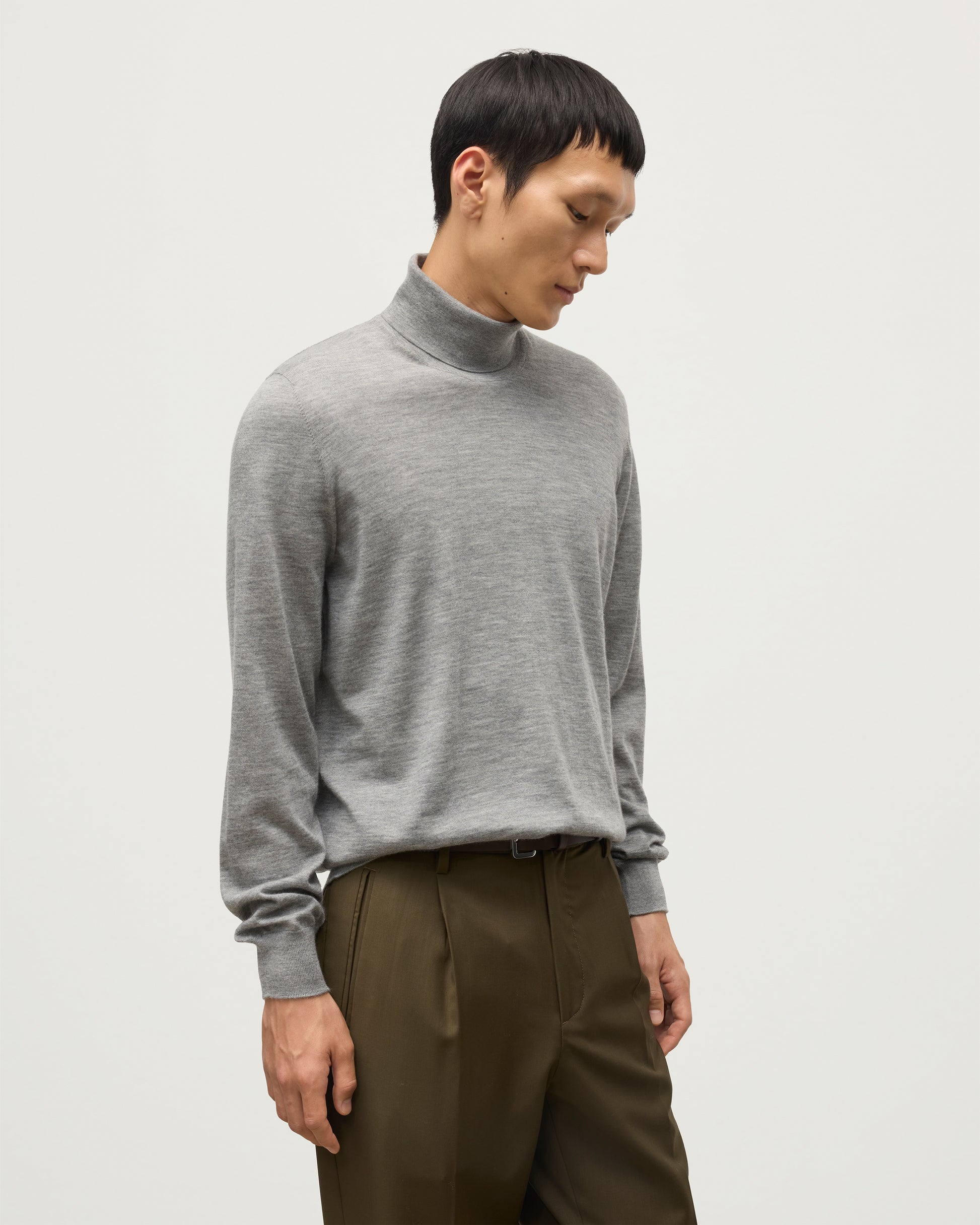 MODEL WEARS JOHNSTONS OF ELGIN MENS SUPERFINE FIN ROLL COLLAR GREY 100% SUPERFINE CASHMERE WITH OLIVE GREEN TROUSERS KAI05333HA4253