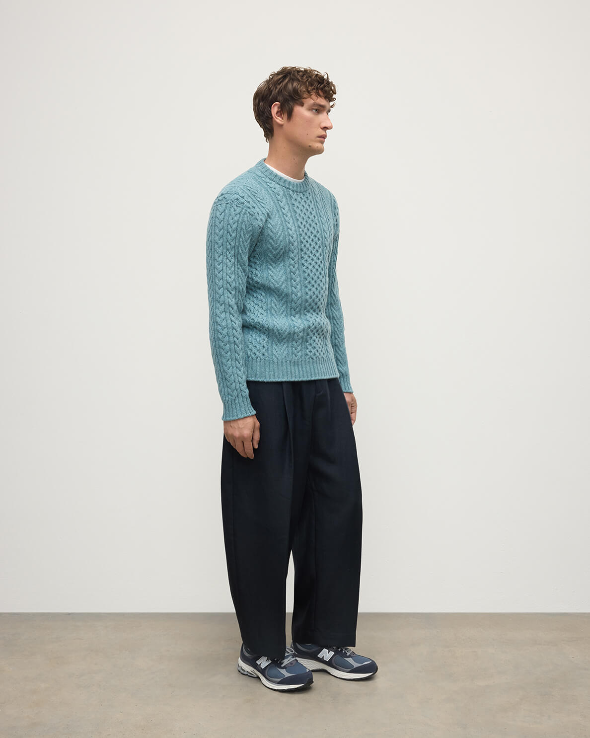 Model wearing Johnstons of Elgin AW25 Men's Knitwear Seascape Aran Cable Green Cashmere Jumper Side KAI05336HC0038