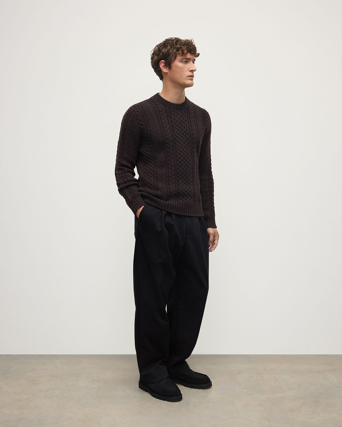 Model wearing Johnstons of Elgin AW25 Men's Knitwear Molasses Aran Cable Brown Cashmere Jumper Side KAI05336SB7290
