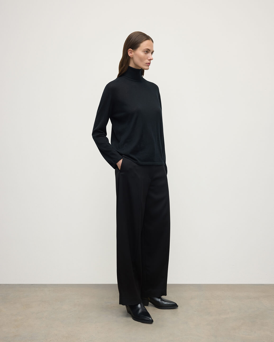 Model wears Johnstons of Elgin AW25 Women's Knitwear Black Superfine Cashmere Black Roll Neck Jumper side View KAI05607SA7146