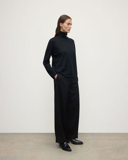 Model wears Johnstons of Elgin AW25 Women's Knitwear Black Superfine Cashmere Black Roll Neck Jumper side View KAI05607SA7146