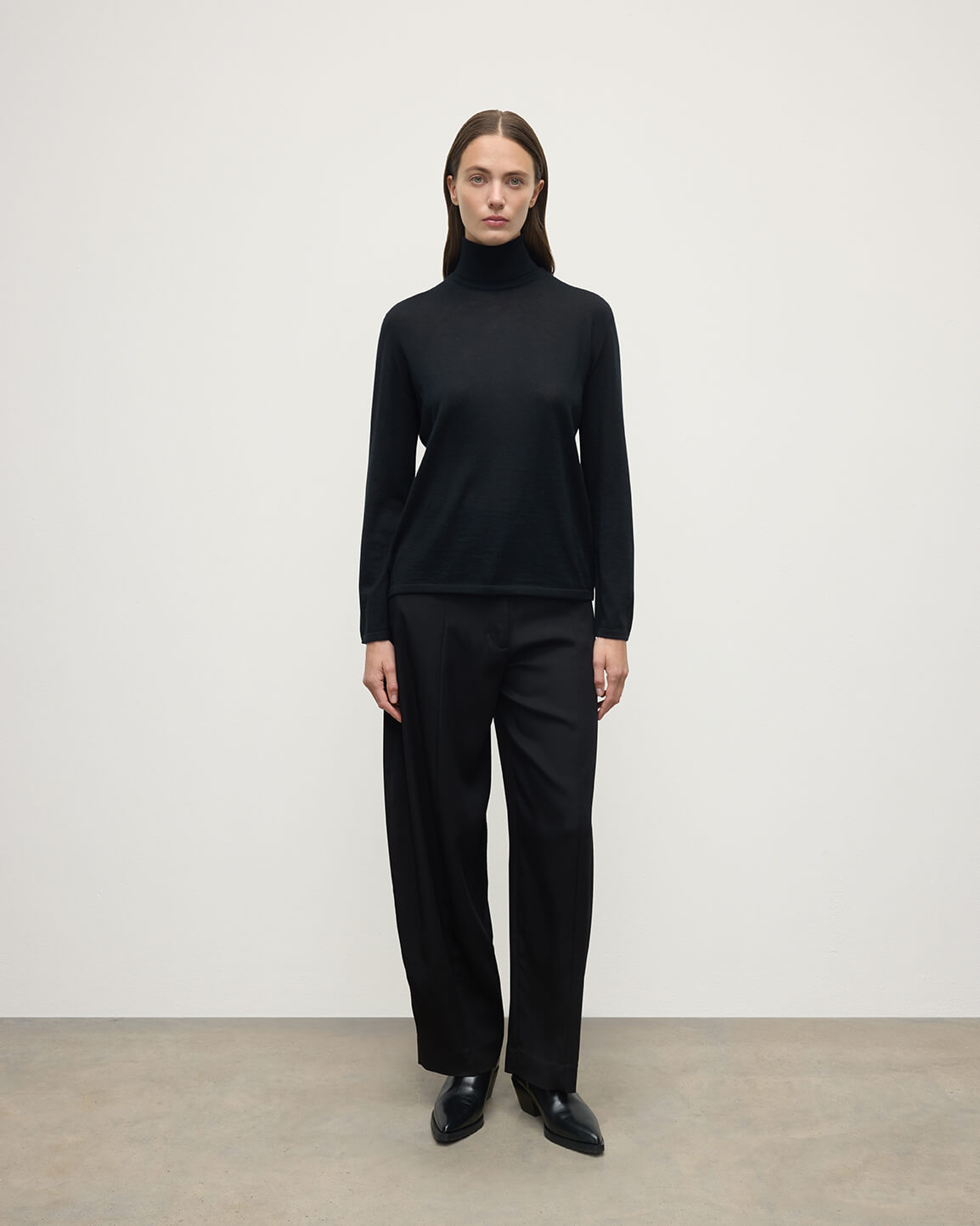 Model wears Johnstons of Elgin AW25 Women's Knitwear Black Superfine Cashmere Black Roll Neck Jumper front View KAI05607SA7146