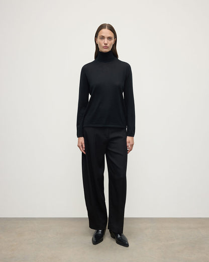 Model wears Johnstons of Elgin AW25 Women's Knitwear Black Superfine Cashmere Black Roll Neck Jumper front View KAI05607SA7146