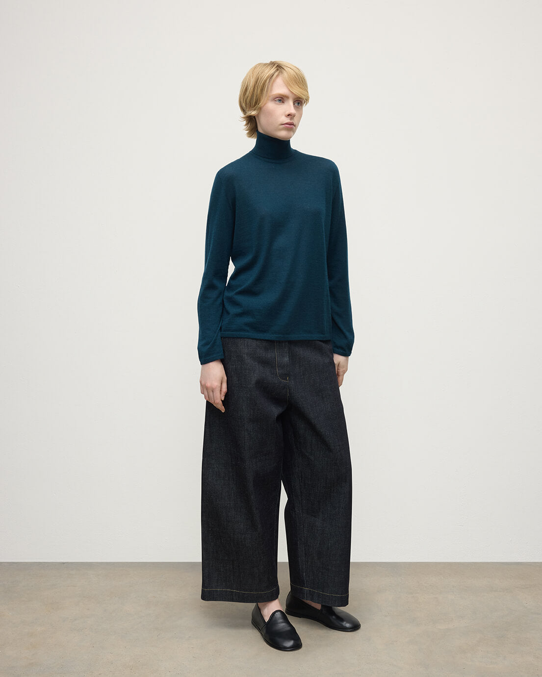 Model wears Johnstons of Elgin AW25 Women's Knitwear Bottle Green Superfine Cashmere Green Roll Neck Jumper Side View  KAI05607SC7344