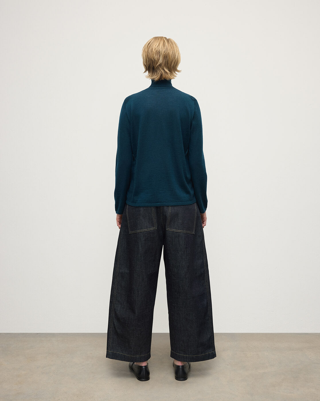 Model wears Johnstons of Elgin AW25 Women's Knitwear Bottle Green Superfine Cashmere Green Roll Neck Jumper Back View  KAI05607SC7344