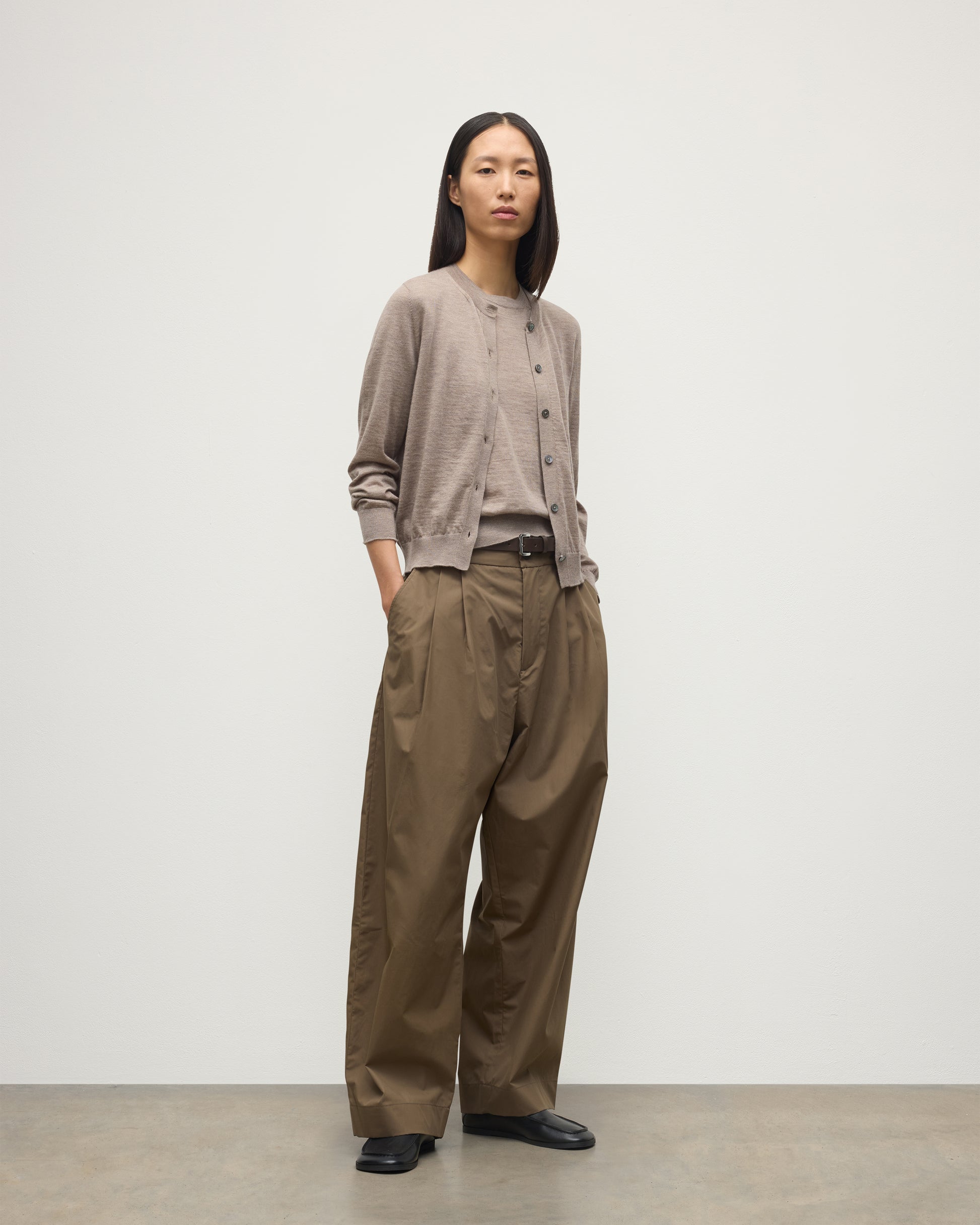 MODEL WEARING JOHNSTONS OF ELGIN WOMENS HONOR CREW CARDIGAN LIGHT BROWN 100% SUPERFINE CASHMERE WITH BROWN WIDE LEG TROUSERS AND BLACK LOAFERS KAI05708HB0273