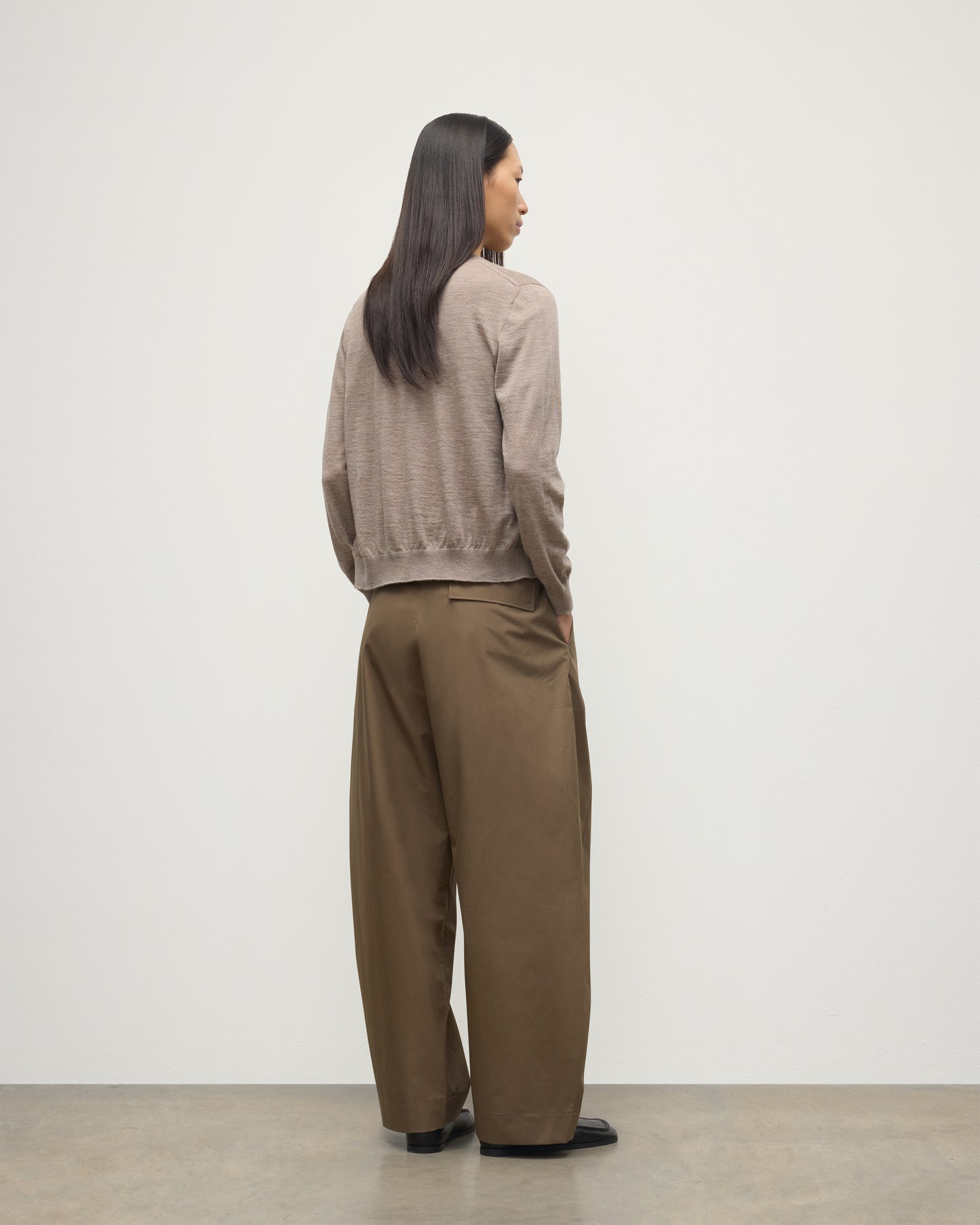 BACK OF MODEL WEARING JOHNSTONS OF ELGIN WOMENS HONOR CREW CARDIGAN LIGHT BROWN 100% SUPERFINE CASHMERE OVER A MATCHING CASHMERE T-SHIRT WITH BROWN WIDE LEG TROUSERS  KAI05708HB0273