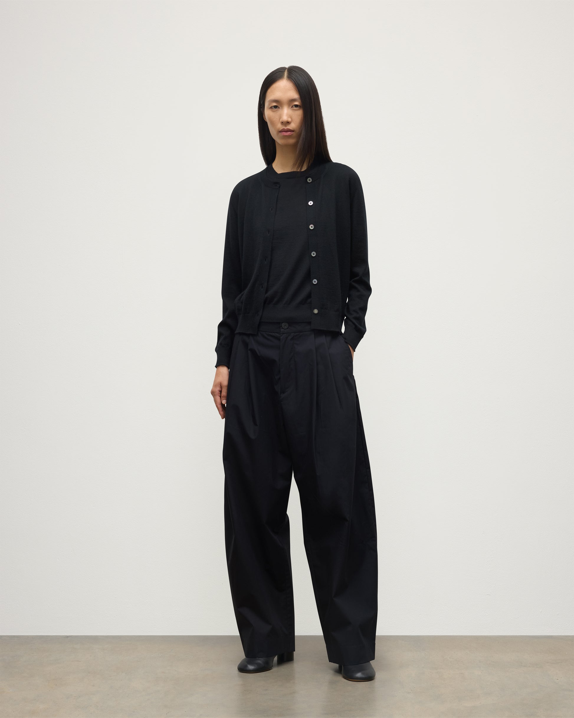 MODEL WEARING JOHNSTONS OF ELGIN WOMENS HONOR CREW CARDIGAN BLACK 100% SUPERFINE CASHMERE OVER A MATCHING T-SHIRT AND NAVY WIDE LEG TROUSERS KAI05708SA7146
