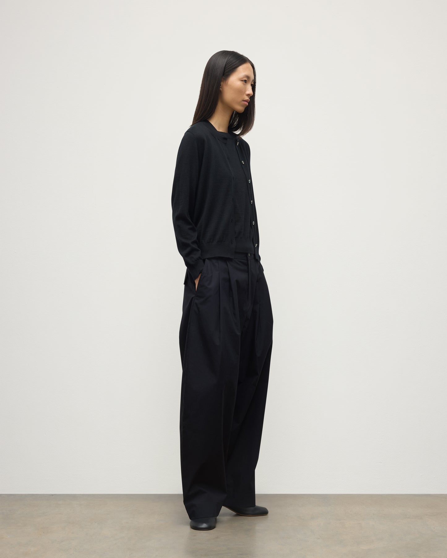 MODEL WEARING JOHNSTONS OF ELGIN WOMENS HONOR CREW CARDIGAN BLACK 100% SUPERFINE CASHMERE OVER A MATCHING T-SHIRT AND NAVY WIDE LEG TROUSERS KAI05708SA7146