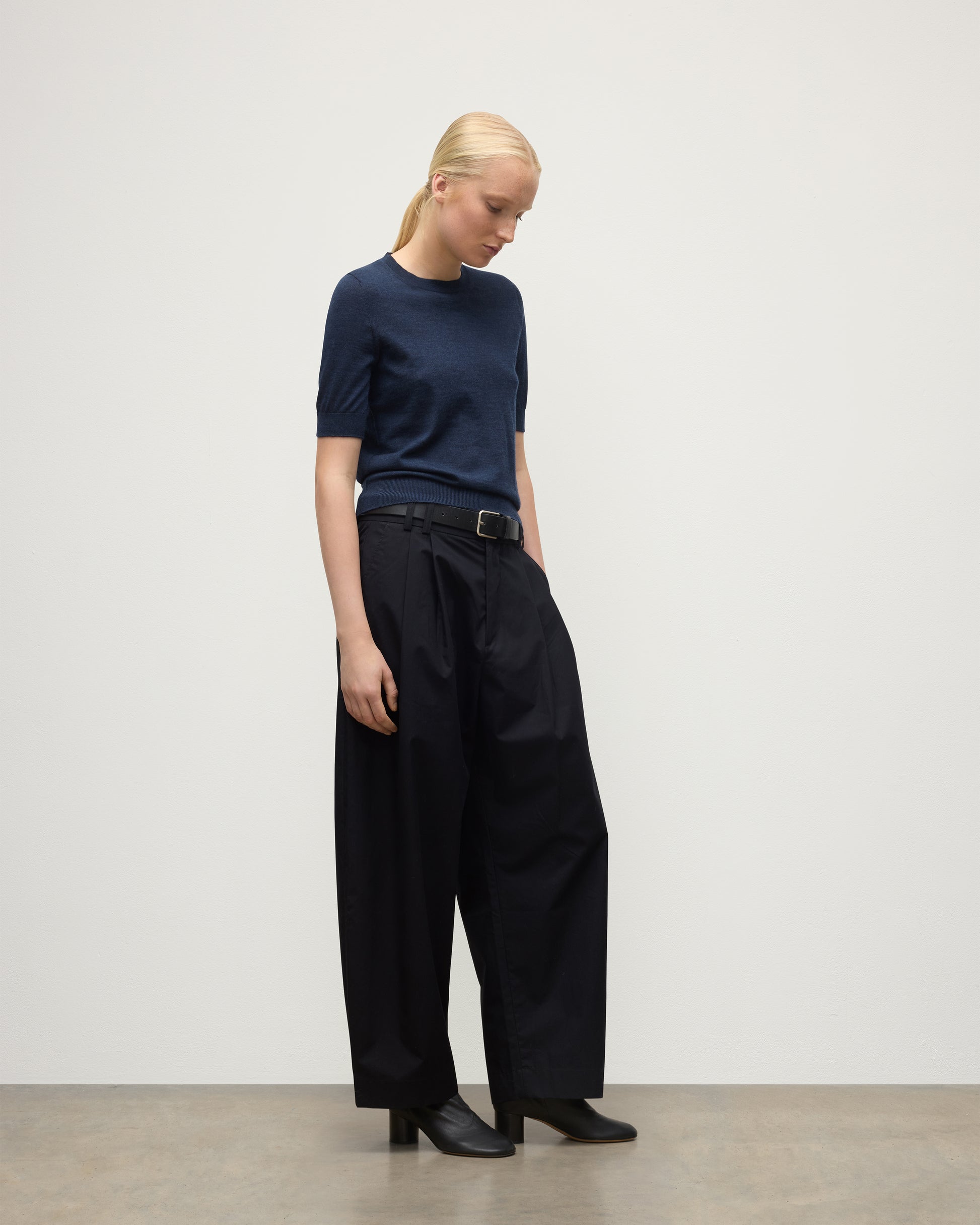 MODEL WEARS JOHNSTONS OF ELGIN WOMENS HONOR SHORT SLEEVE CREW NAVY 100% SUPERFINE CASHMERE WITH NAVY TROUSERS AND BLACK BOOTS KAI05712HD7350