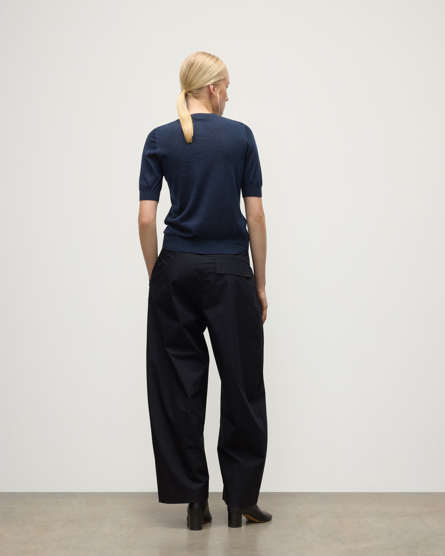 MODEL WEARS JOHNSTONS OF ELGIN WOMENS HONOR SHORT SLEEVE CREW NAVY 100% SUPERFINE CASHMERE WITH NAVY TROUSERS AND BLACK BOOTS KAI05712HD7350