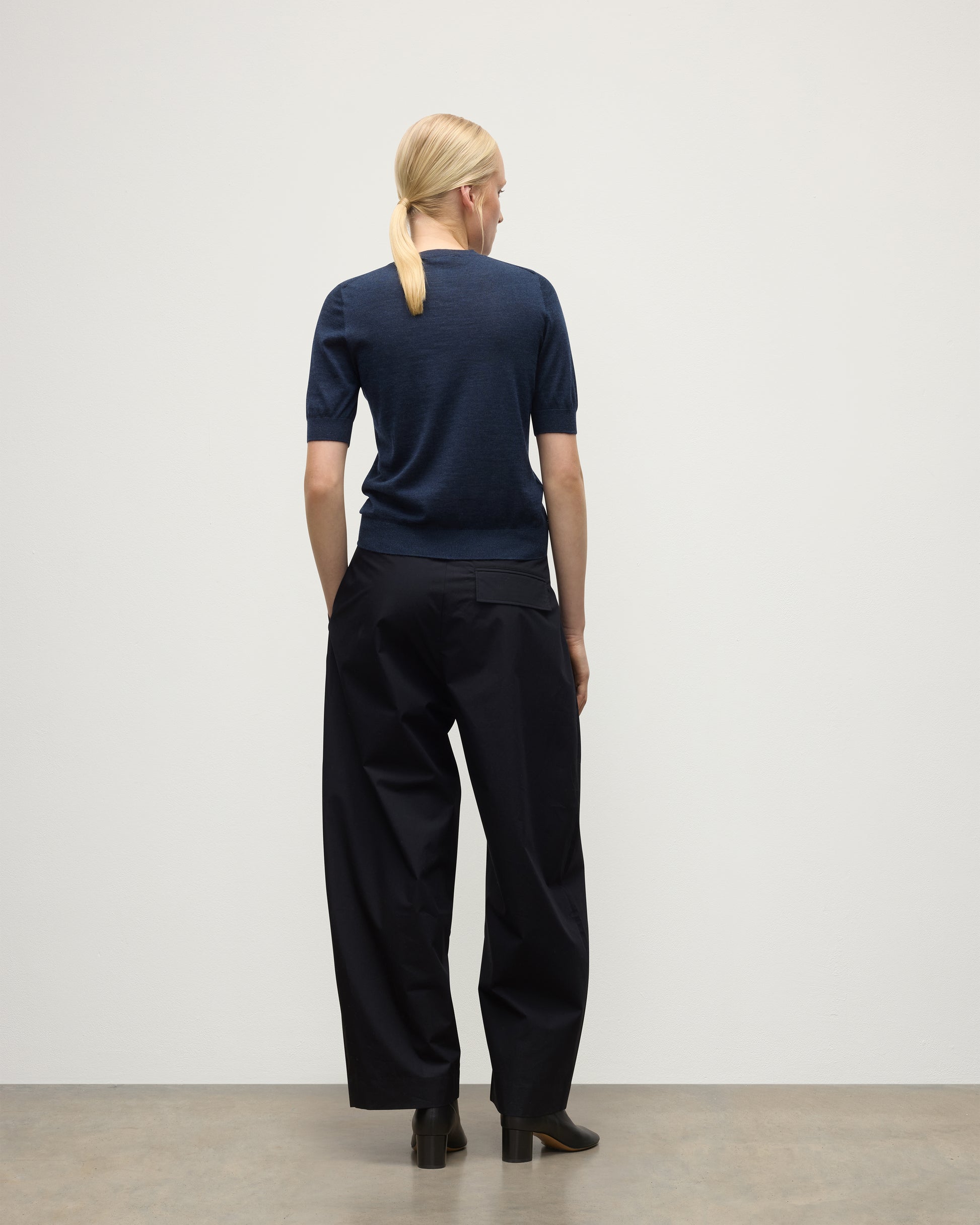 MODEL WEARS JOHNSTONS OF ELGIN WOMENS HONOR SHORT SLEEVE CREW NAVY 100% SUPERFINE CASHMERE WITH NAVY TROUSERS AND BLACK BOOTS KAI05712HD7350