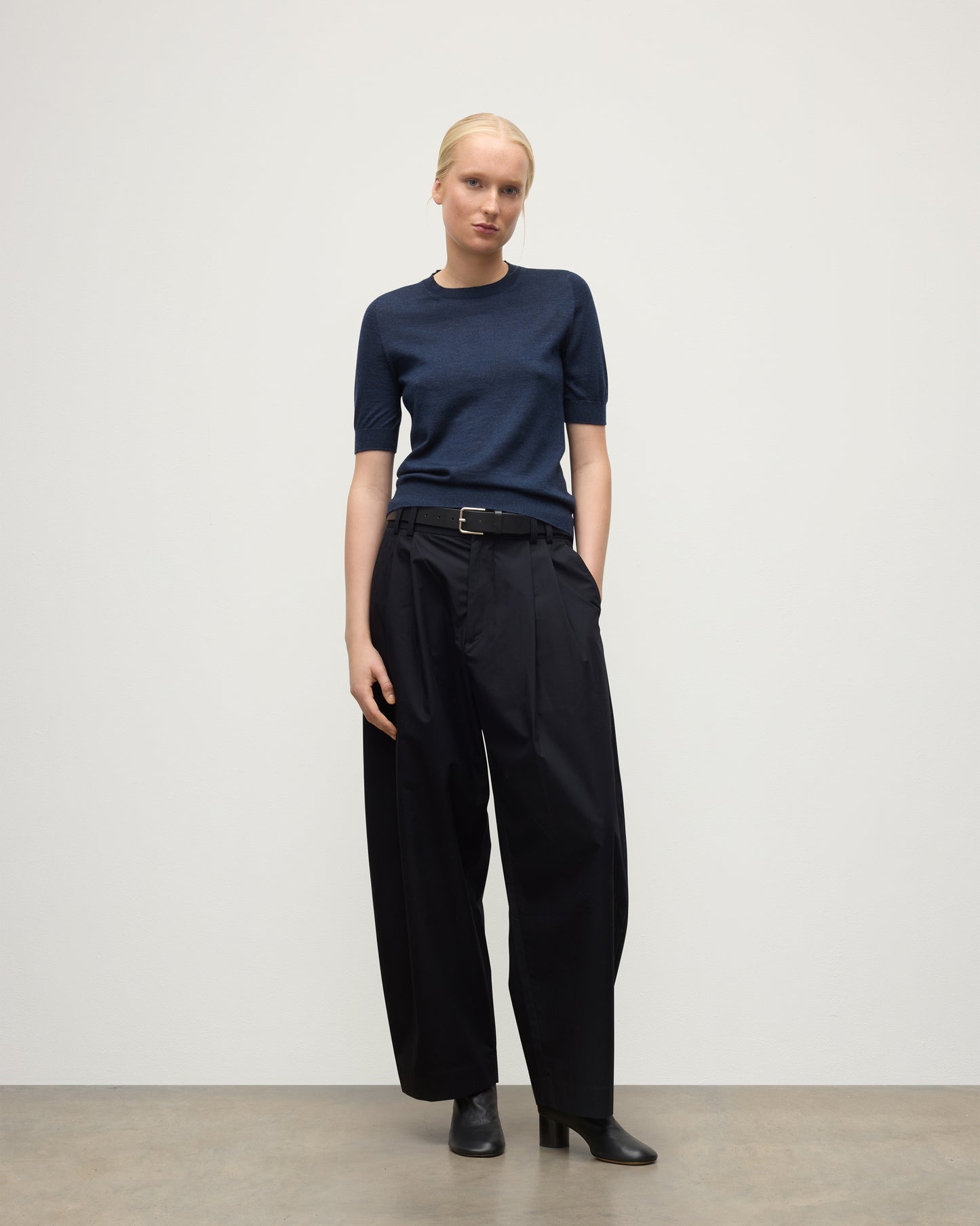 MODEL WEARS JOHNSTONS OF ELGIN WOMENS HONOR SHORT SLEEVE CREW NAVY 100% SUPERFINE CASHMERE WITH NAVY TROUSERS AND BLACK BOOTS KAI05712HD7350