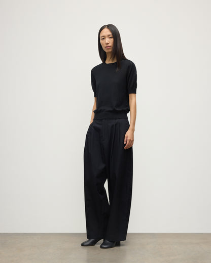 MODEL WEARS JOHNSTONS OF ELGIN WOMENS HONOR SHORT SLEEVE CREW BLACK 100% SUPERFINE CASHMERE WITH BLACK TROUSERS AND BOOTS KAI05712SA7146