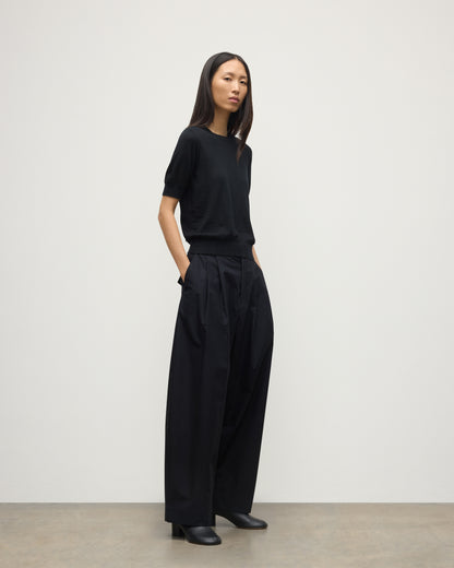 MODEL WEARS JOHNSTONS OF ELGIN WOMENS HONOR SHORT SLEEVE CREW BLACK 100% SUPERFINE CASHMERE WITH BLACK TROUSERS AND BOOTS KAI05712SA7146