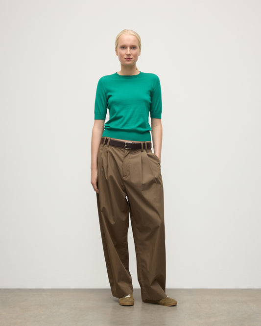 MODEL WEARS JOHNSTONS OF ELGIN WOMENS HONOR SHORT SLEEVE CREW GREEN 100% SUPERFINE CASHMERE WITH BROWN RELAXED TROUSERS AND TRAINERS KAI05712SC4714