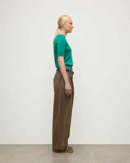 MODEL WEARS JOHNSTONS OF ELGIN WOMENS HONOR SHORT SLEEVE CREW GREEN 100% SUPERFINE CASHMERE WITH BROWN RELAXED TROUSERS AND TRAINERS KAI05712SC4714