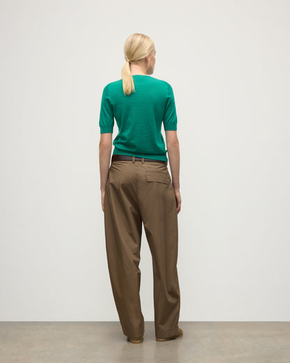BACK OF MODEL WEARS JOHNSTONS OF ELGIN WOMENS HONOR SHORT SLEEVE CREW GREEN 100% SUPERFINE CASHMERE WITH BROWN RELAXED TROUSERS AND TRAINERS KAI05712SC4714