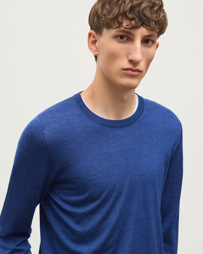 A man wearing a heathered blue long-sleeve crewneck shirt, photographed against a plain light gray background. JOHNSTONS OF ELGIN FIN CREW SUPERFINE CASHMERE CREW NECK SWEATER - 3 PLY BLUE 100% CASHMERE KAI05717HD4509