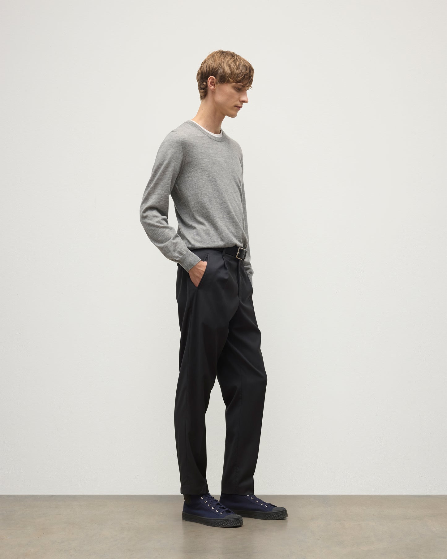 MODEL WEARS JOHNSTONS OF ELGIN MENS FIN SUPERFINE CREW GREY 100% SUPERFINE CASHMERE  OVER A WHITE T-SHIRT WITH GREY TROUSERS KAI05717HA4253