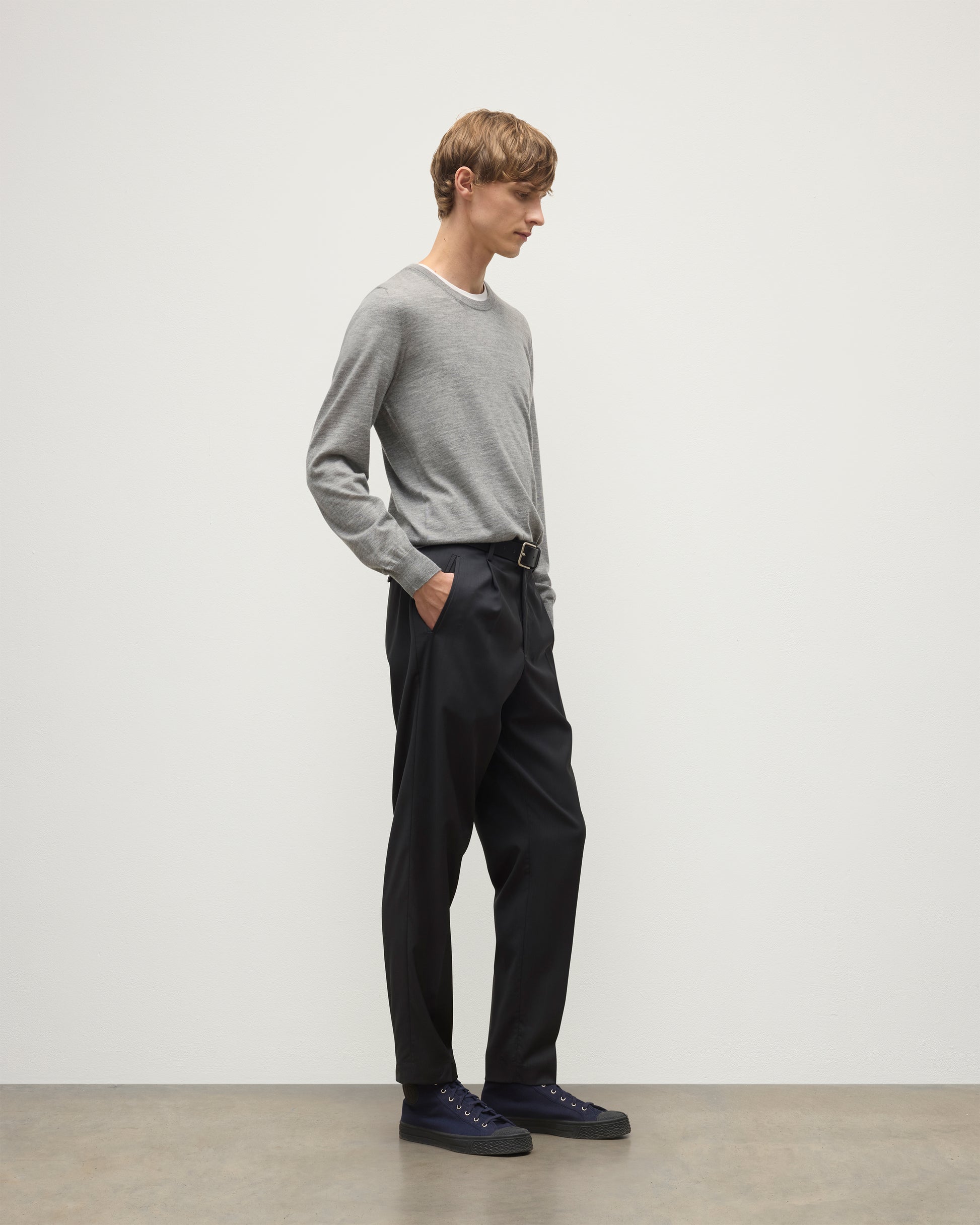 MODEL WEARS JOHNSTONS OF ELGIN MENS FIN SUPERFINE CREW GREY 100% SUPERFINE CASHMERE  OVER A WHITE T-SHIRT WITH GREY TROUSERS KAI05717HA4253