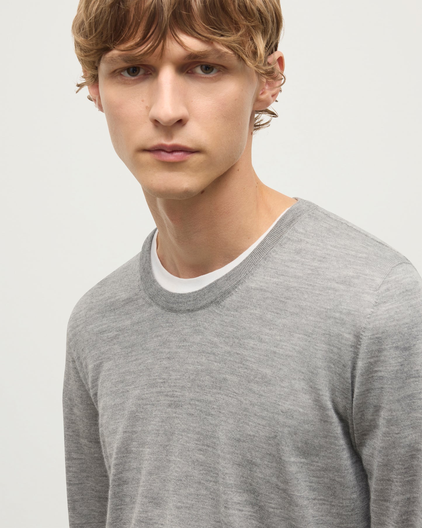 MODEL WEARS JOHNSTONS OF ELGIN MENS FIN SUPERFINE CREW GREY 100% SUPERFINE CASHMERE  OVER A WHITE T-SHIRT KAI05717HA4253