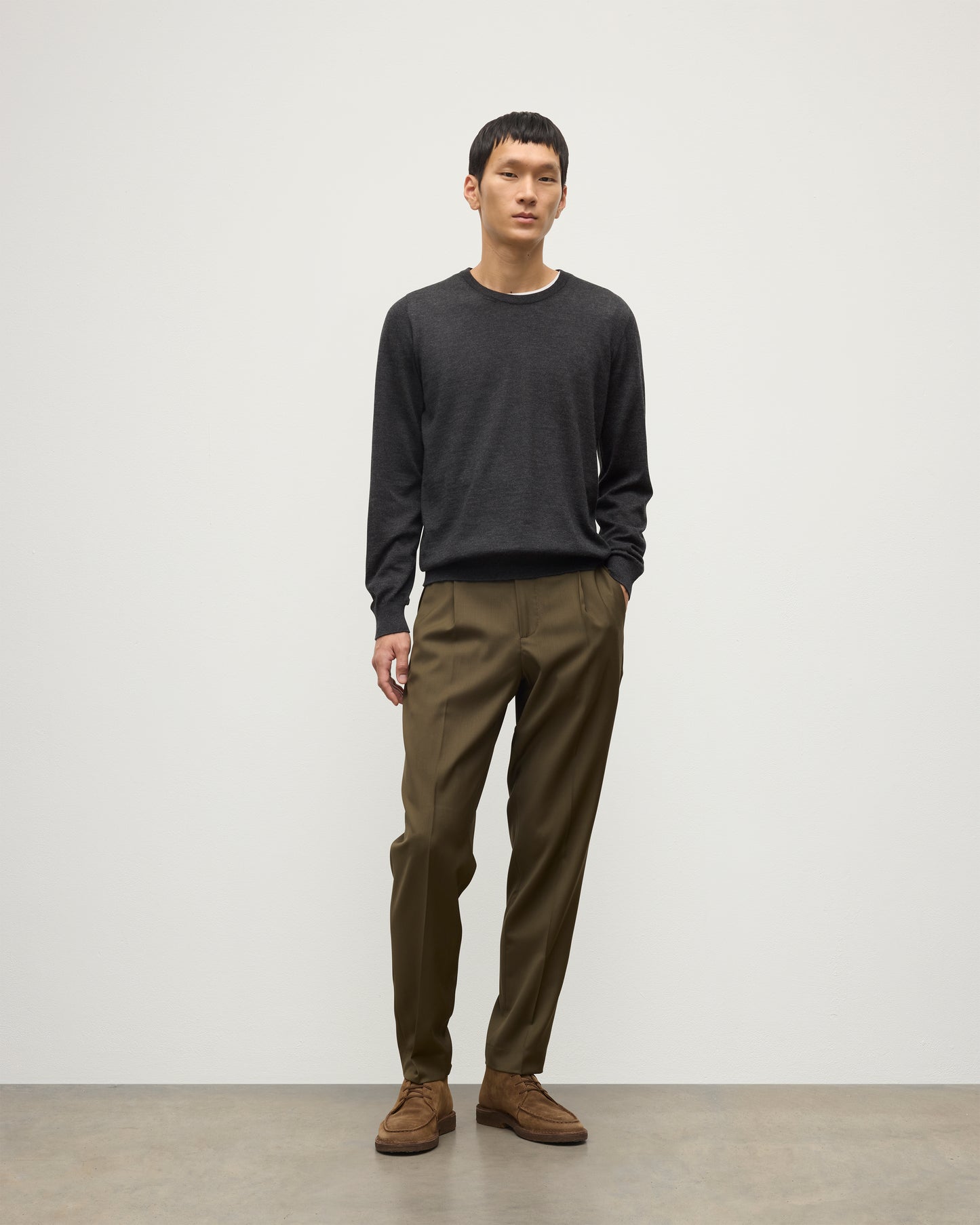 MODEL WEARS JOHNSTONS OF ELGIN MENS FIN SUPERFINE CREW GREY 100% SUPERFINE CASHMERE OVER A WHITE T-SHIRT WITH OLIVE GREEN TROUSERS KAI05717HA7218