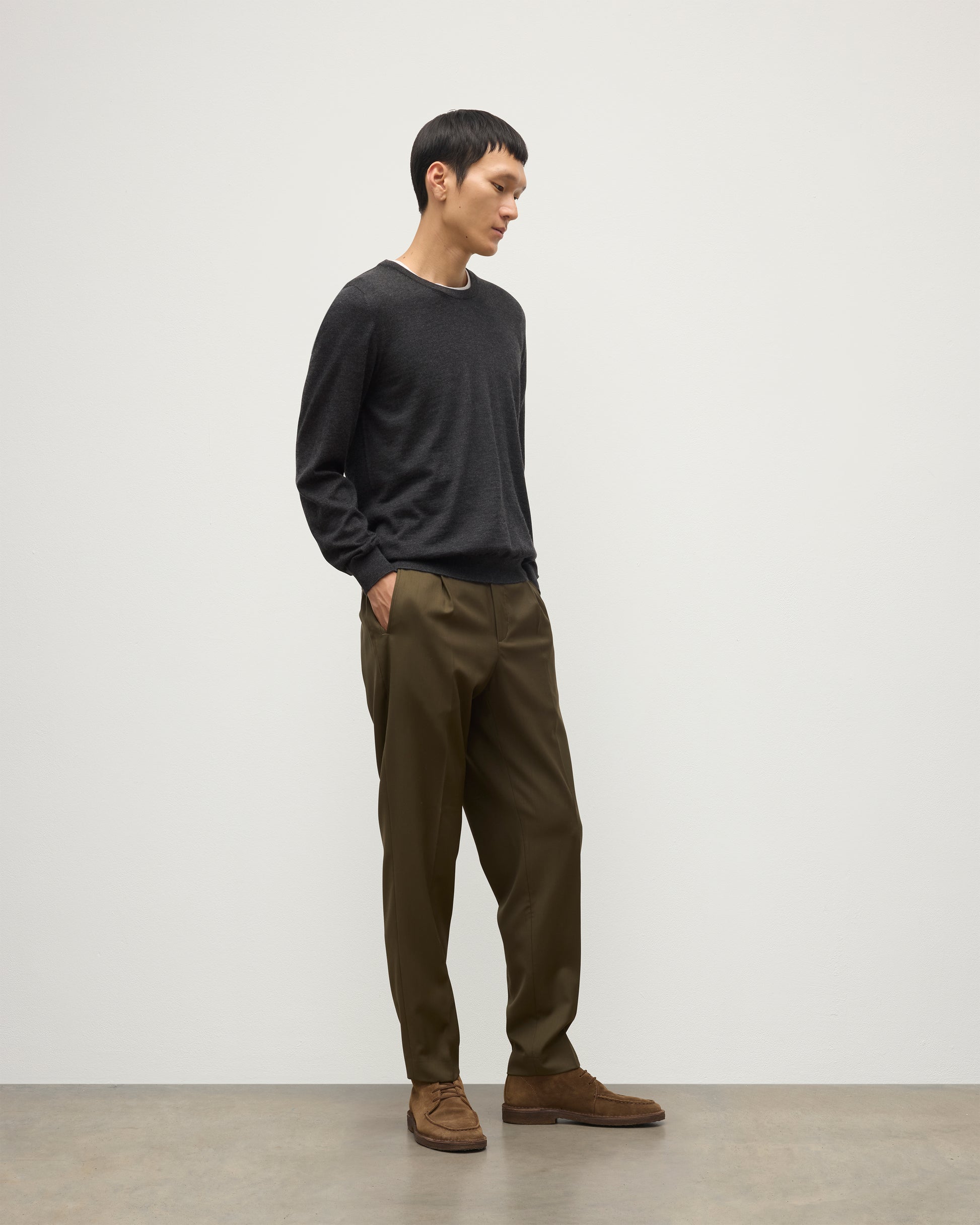 MODEL WEARS JOHNSTONS OF ELGIN MENS FIN SUPERFINE CREW GREY 100% SUPERFINE CASHMERE OVER A WHITE T-SHIRT WITH OLIVE GREEN TROUSERS KAI05717HA7218