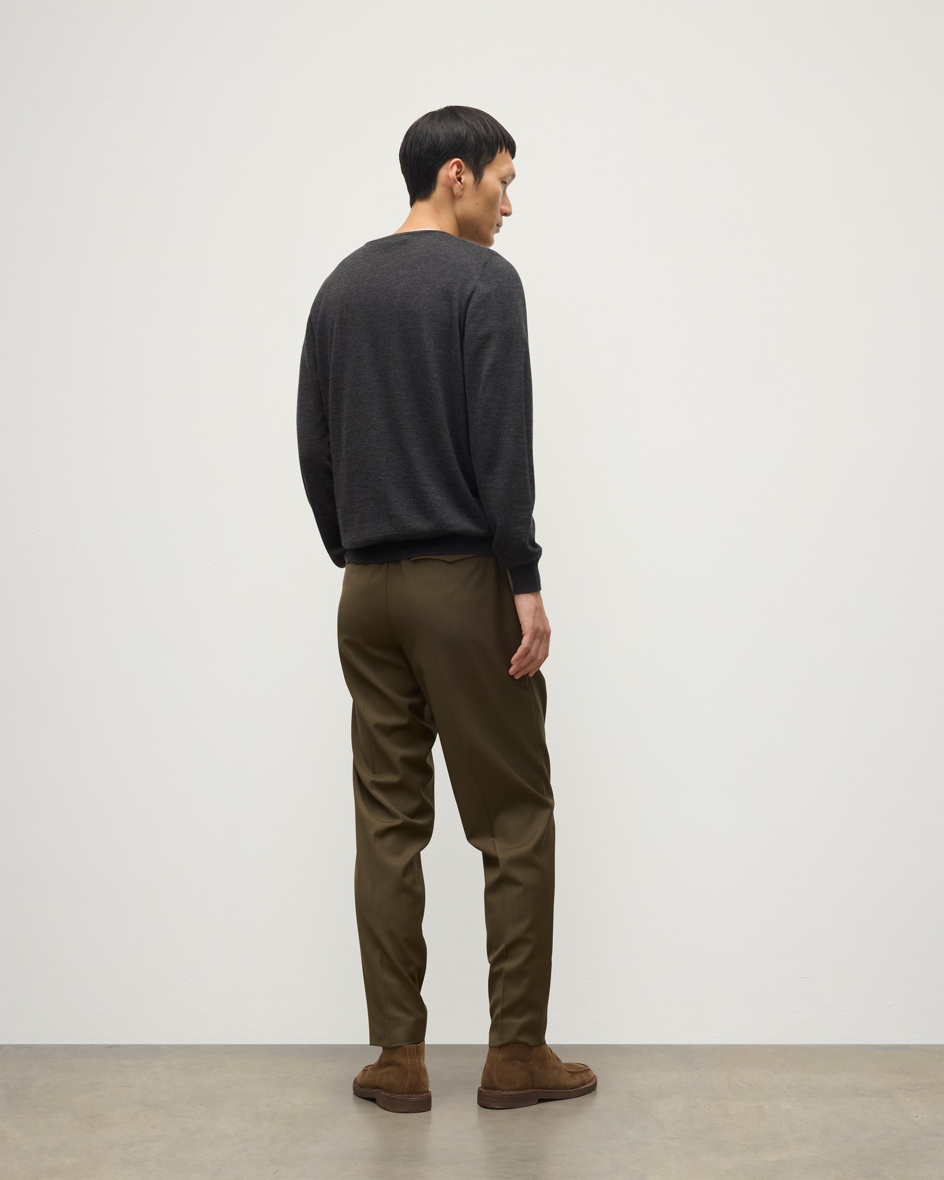 MODEL WEARS JOHNSTONS OF ELGIN MENS FIN SUPERFINE CREW GREY 100% SUPERFINE CASHMERE OVER A WHITE T-SHIRT WITH OLIVE GREEN TROUSERS KAI05717HA7218